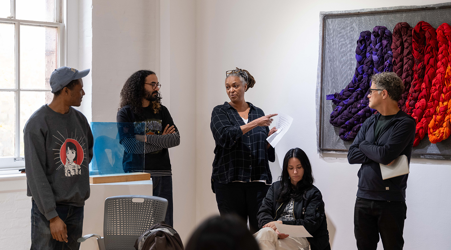 Students and faculty gather for an art critique.