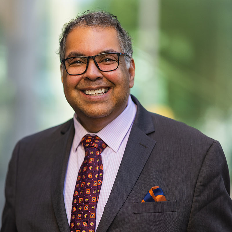 a man wearing glasses and a suit and tie smiling