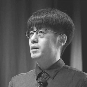 Man with dark hair wearing glasses and a dark collared shirt