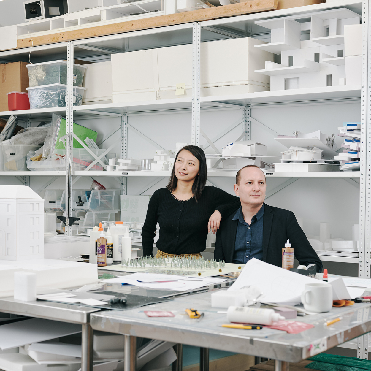 Man and woman posing in front of white shelves
