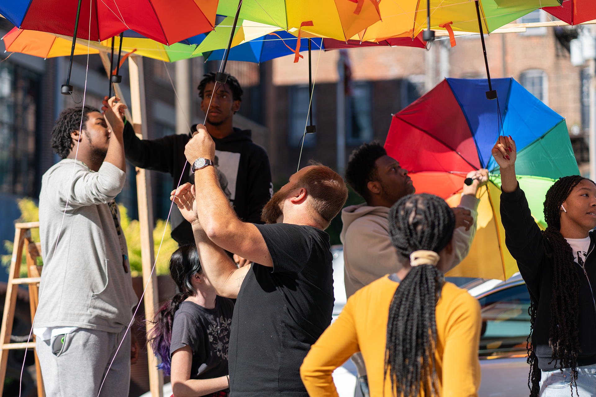 https://www.aap.cornell.edu/A%20group%20of%20people%20work%20together%20to%20put%20up%20rainbow%20umbrellas
