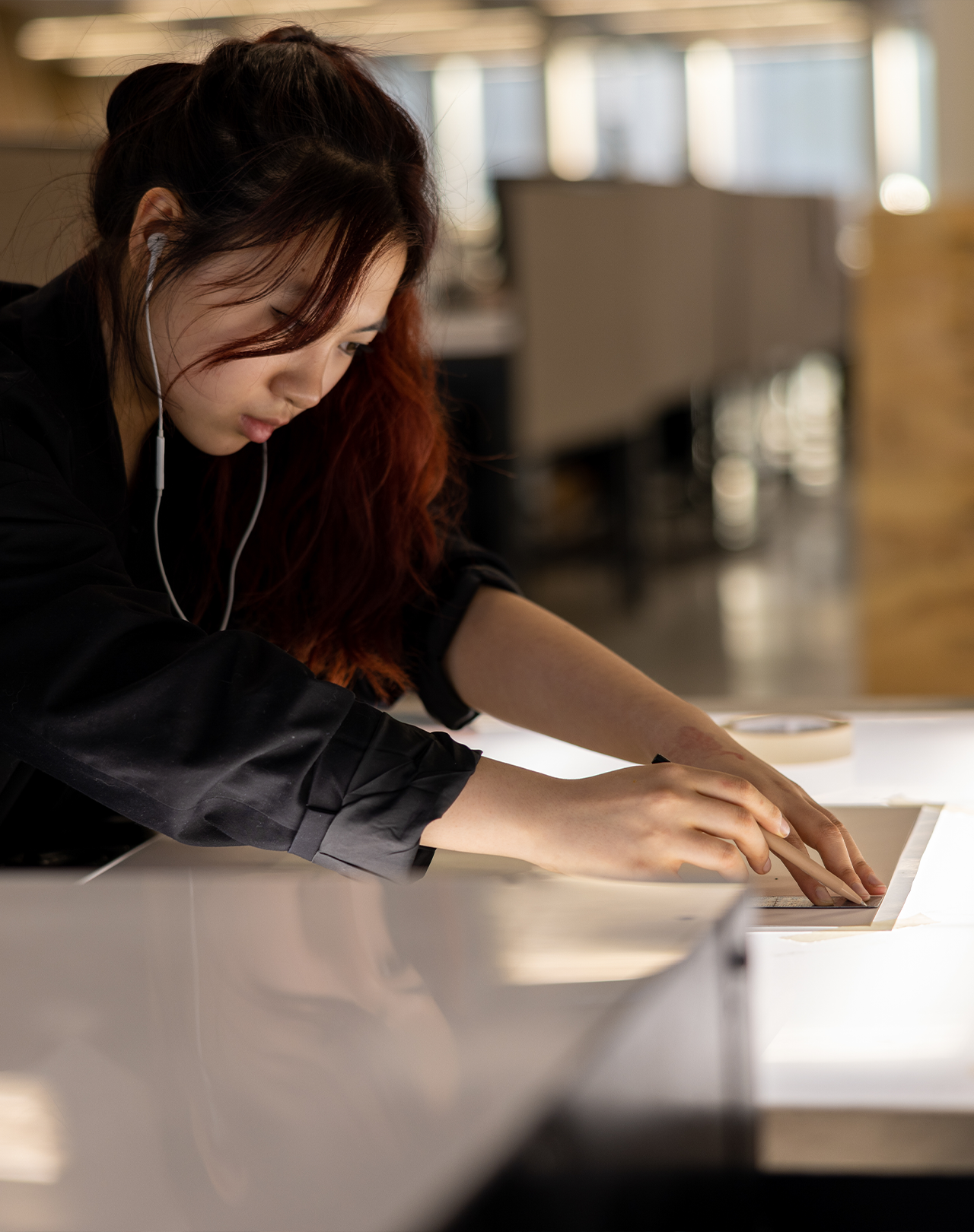 A person drawing on a piece of paper at a light table.