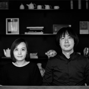 Man and woman with dark hair and wearing black clothing standing side by side