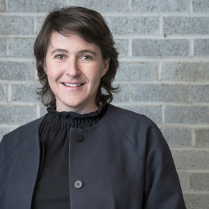 A woman in front of a concrete wall smiling at the camera