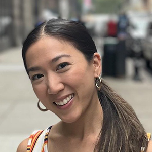 A woman with long dark hair in a ponytail smiles at the camera.