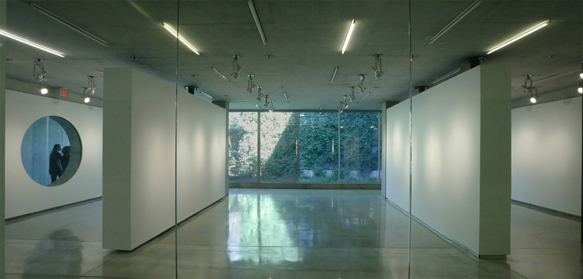 Room with two glass walls (north and south) with two moveable room dividers and a round window on the west wall