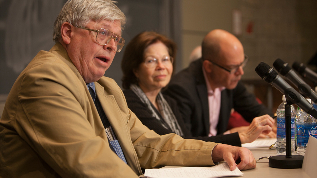 Three people seated at a table with a microphone in front of each.