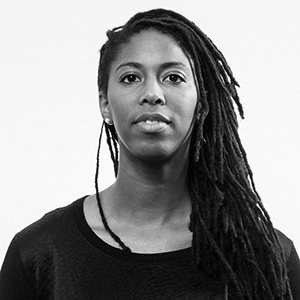 A person with long braids and a dark top.