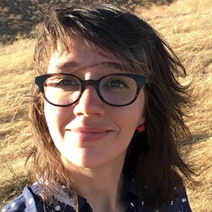 A woman with brown hair and glasses smiles at the camera.