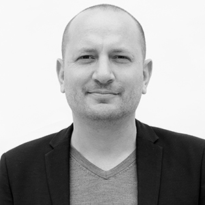 a person with shaved head and a dark jacket