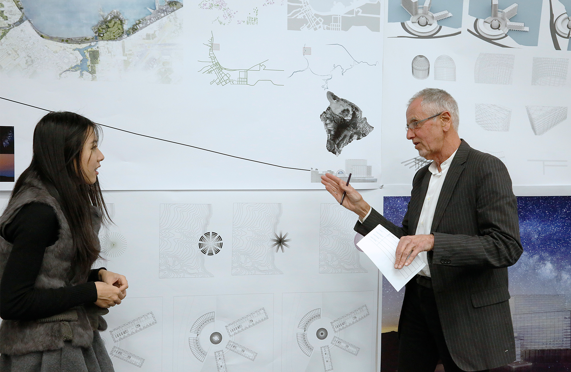 two people speaking in front of a large architectural diagram
