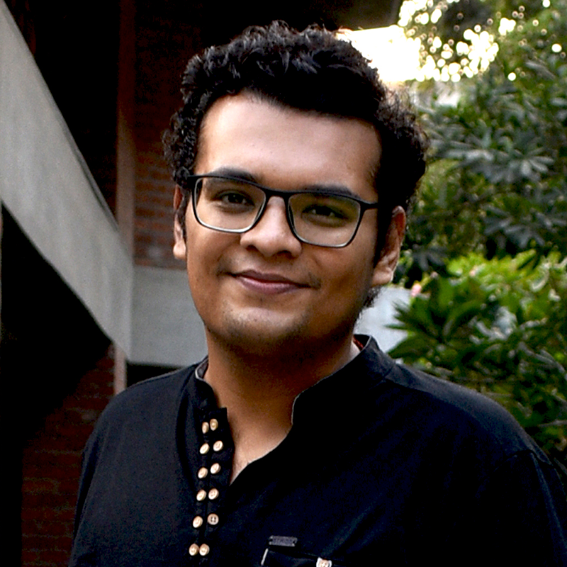 A smiling man with dark curly hair and light brown skin