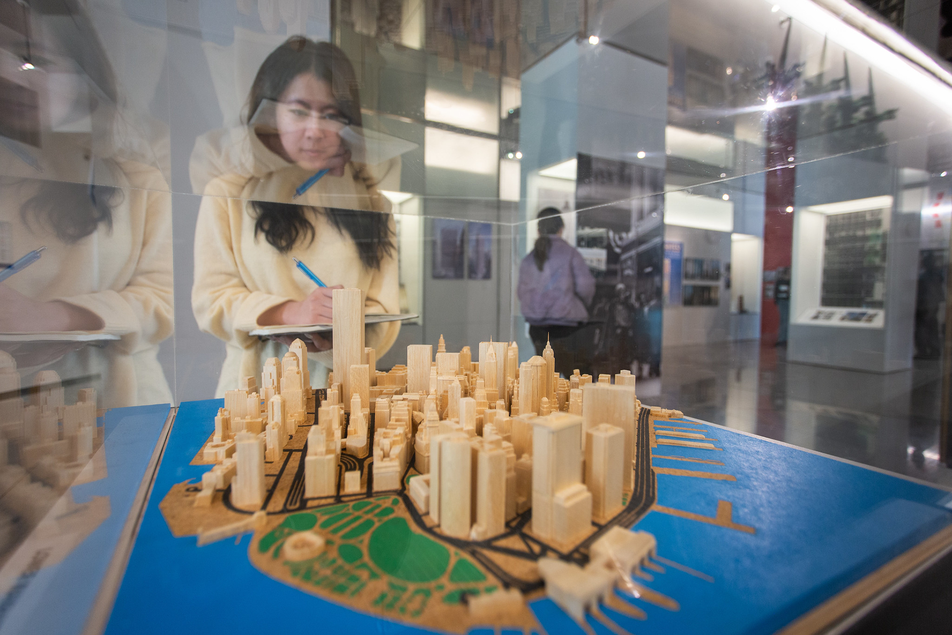 Woman looking at a museum exhibition of a city inside a glass case