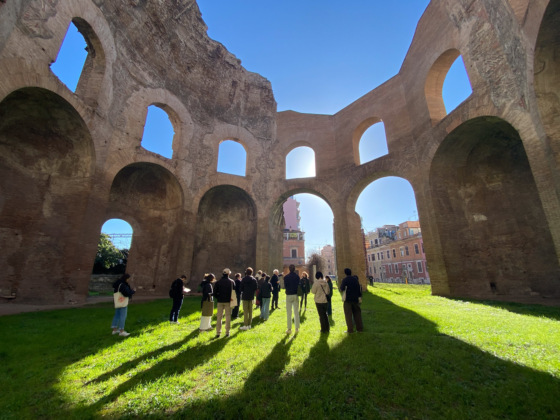 People gathered inside ruin walls on a bright green lawn
