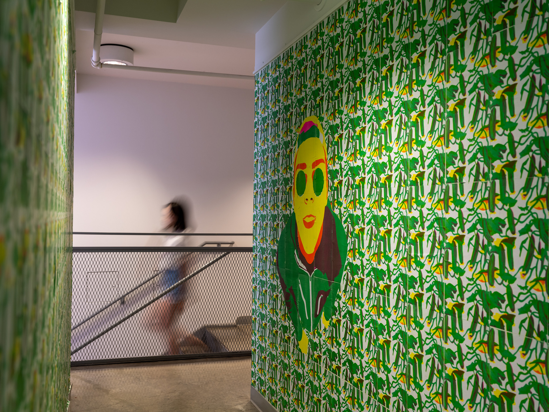 Bright green geometric mural and person descending stairs in the background