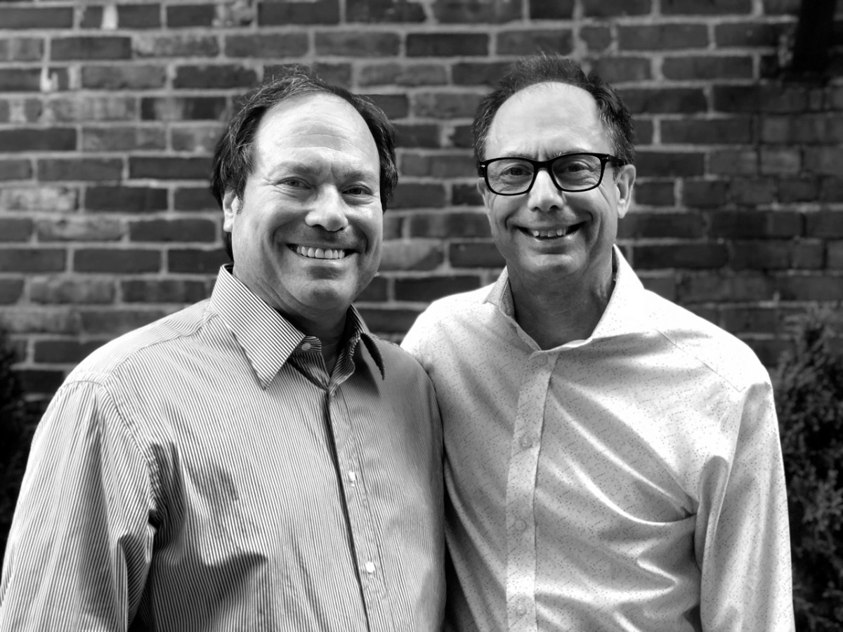 two men wearing dress shirts standing next to one another