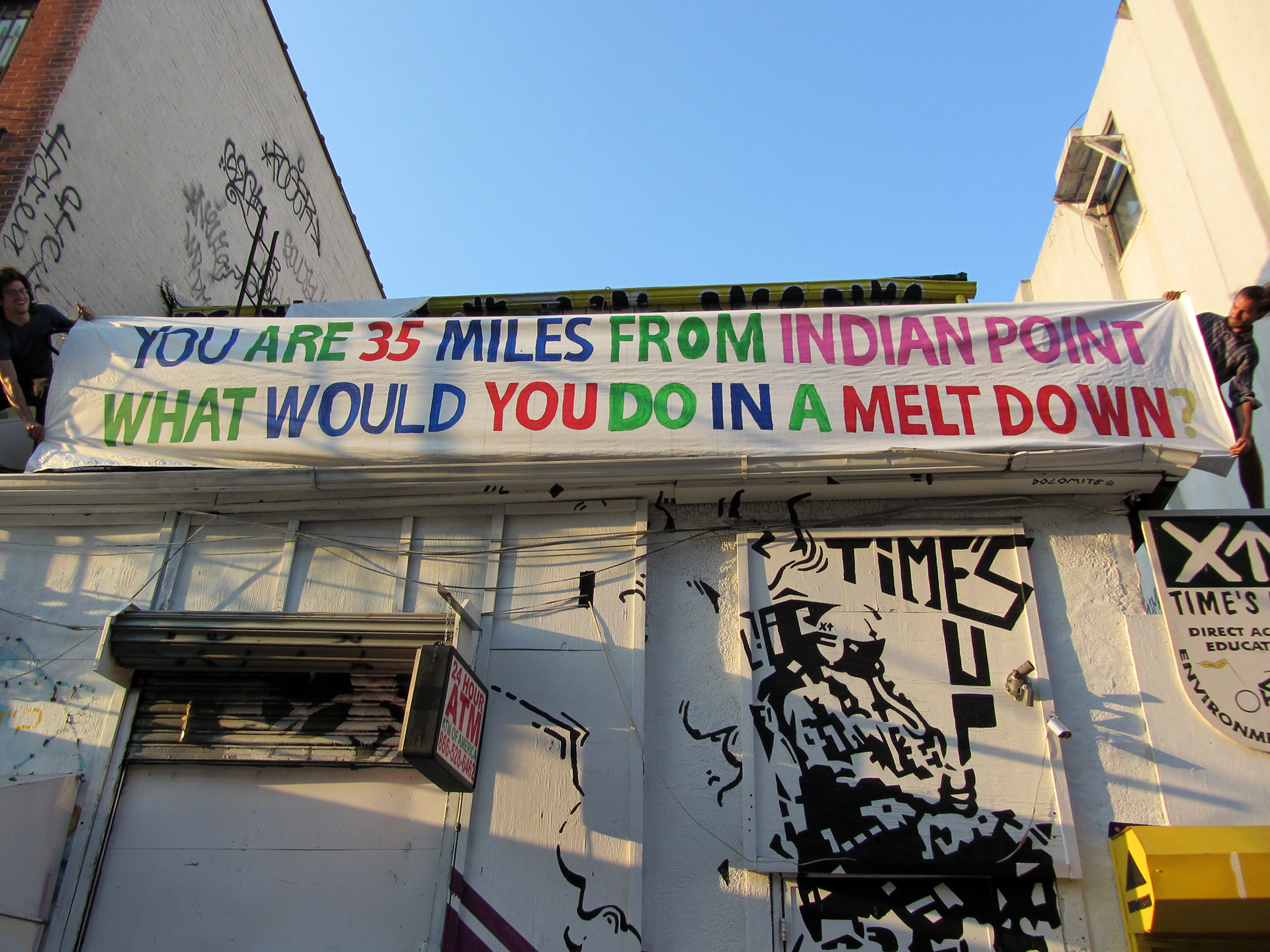 White brick building with large sign draped out from the roof.