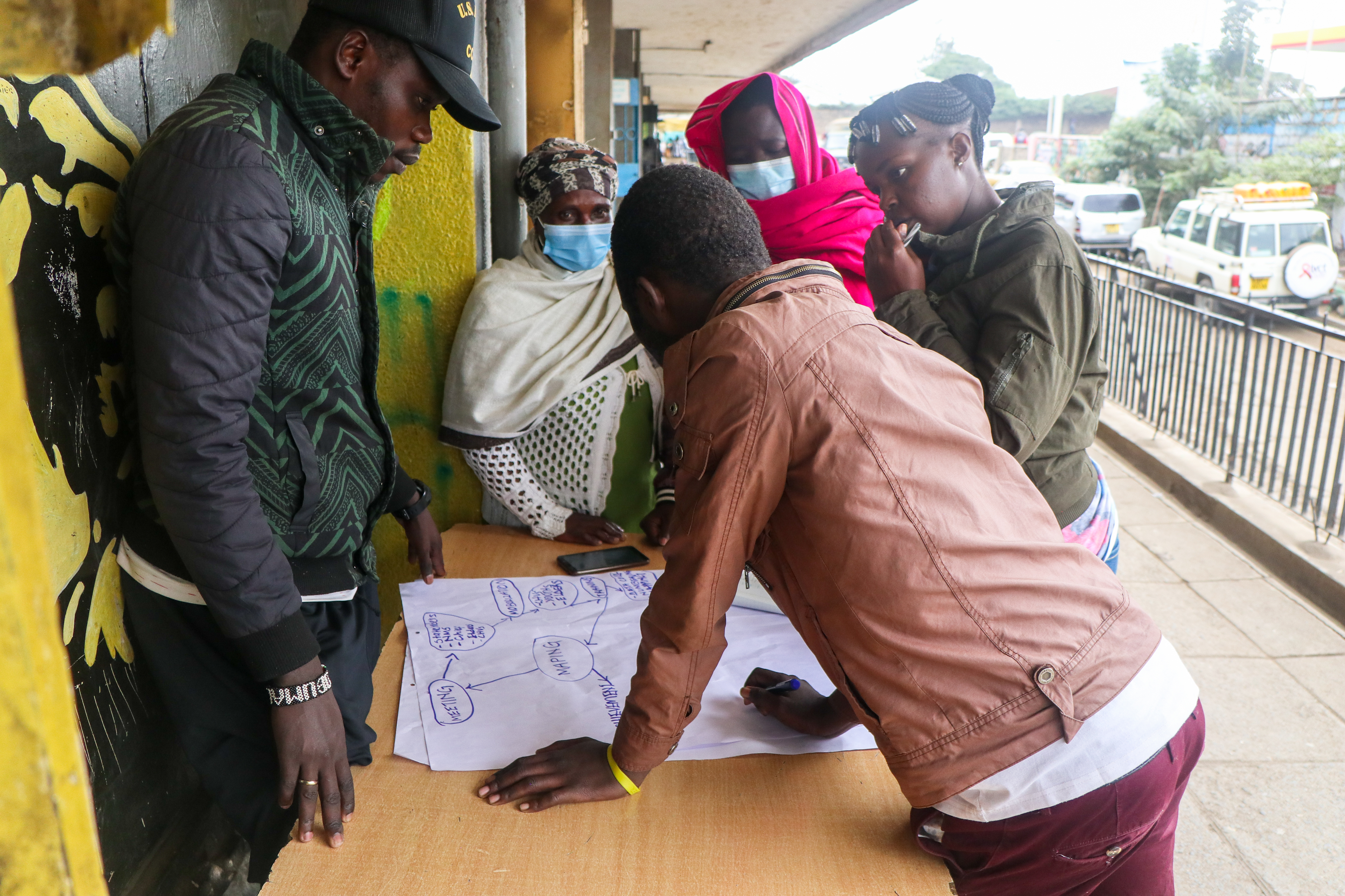 People gathered around a stable studying a hand-drawn chart