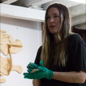 A person with green surgical gloves working on an art piece.