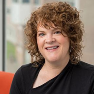 A woman with short curly hair smiling at the camera