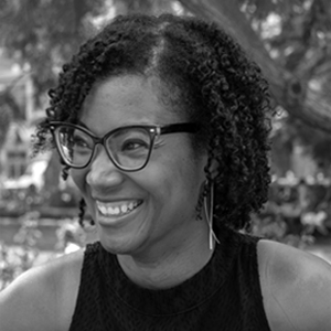 Woman with dark hair wearing glasses and black sleeveless top.