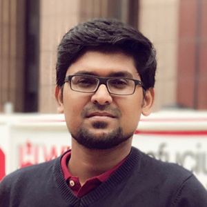 A person with glasses, short black hair, and a red and blue shirt.