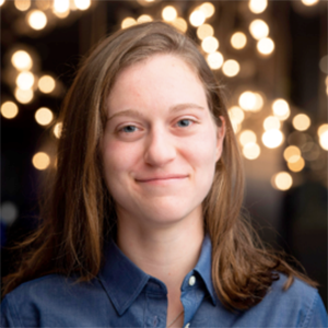 A woman with shoulder-length brown hair and a blue shirt smiles at the camera.