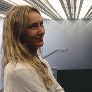 A person with long blonde hair standing underneath large lights in a building.