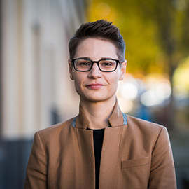 A person with glasses and a brown coat.