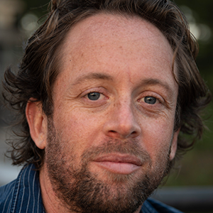 a person looking at the camera wearing a blue striped collared shirt