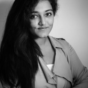 A black and white photo of a woman with long dark hair looking at the camera and smiling