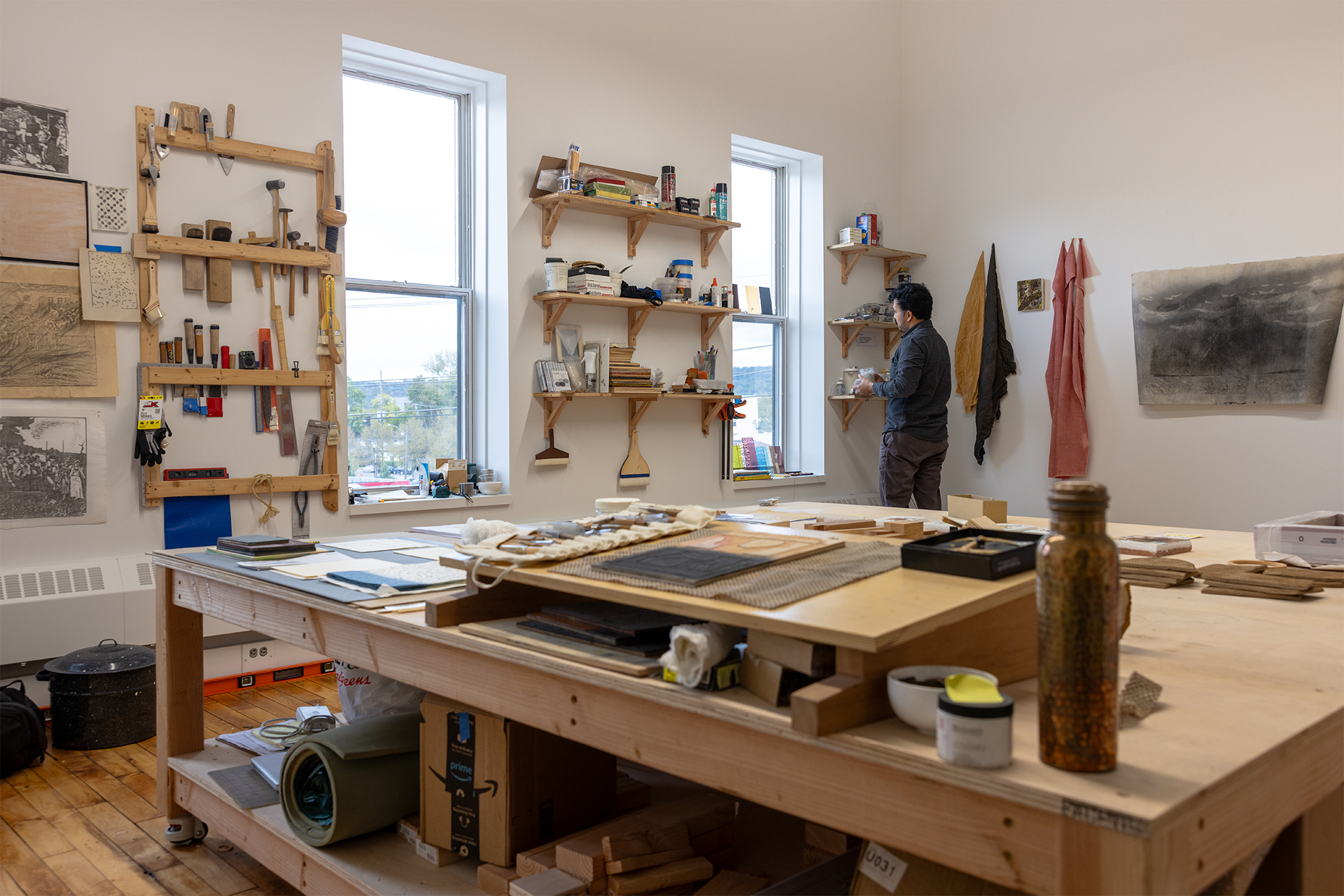 Man looking out the window in a large studio space filled with works of art.