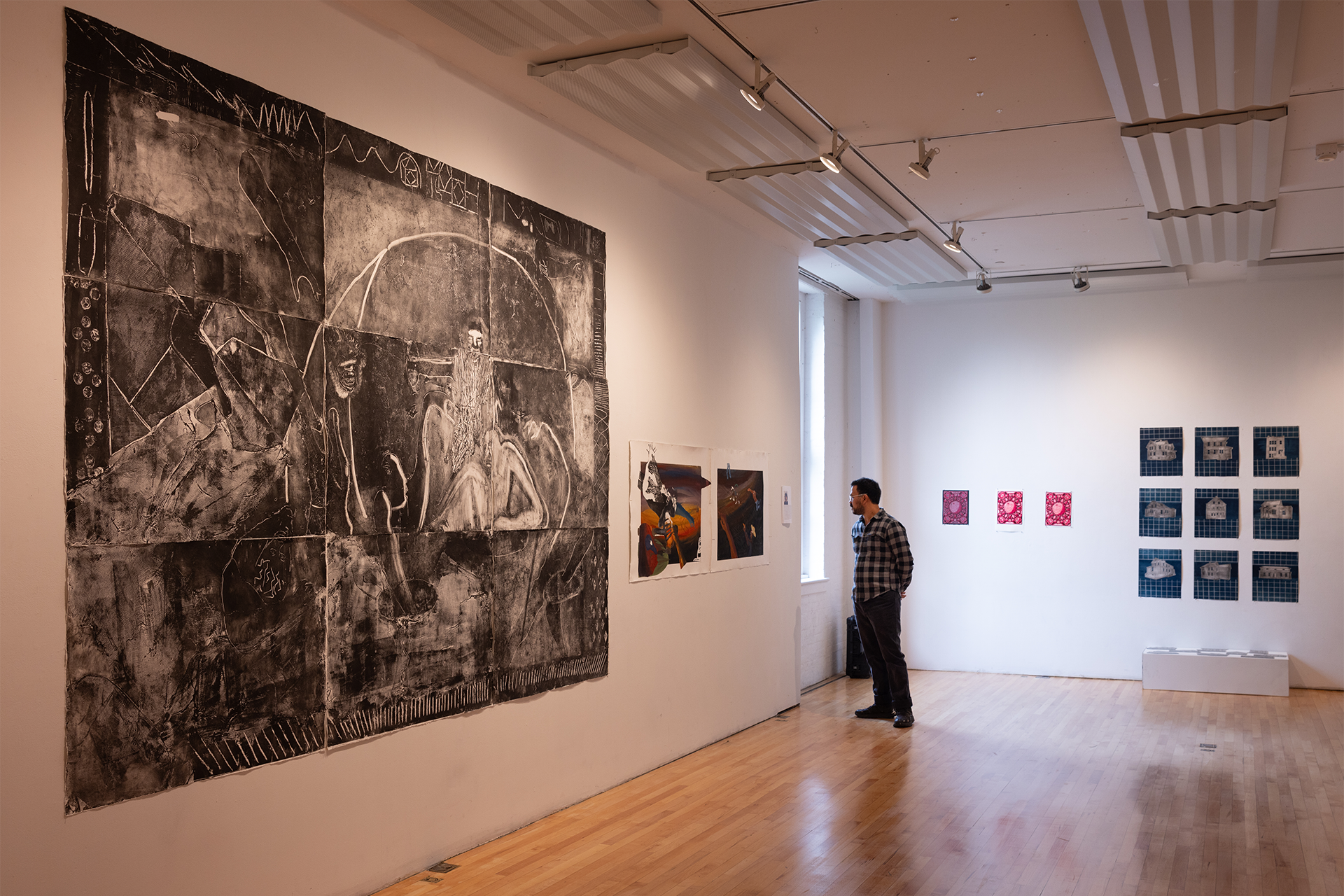 Man in a gallery looking at the drawings hung on the walls