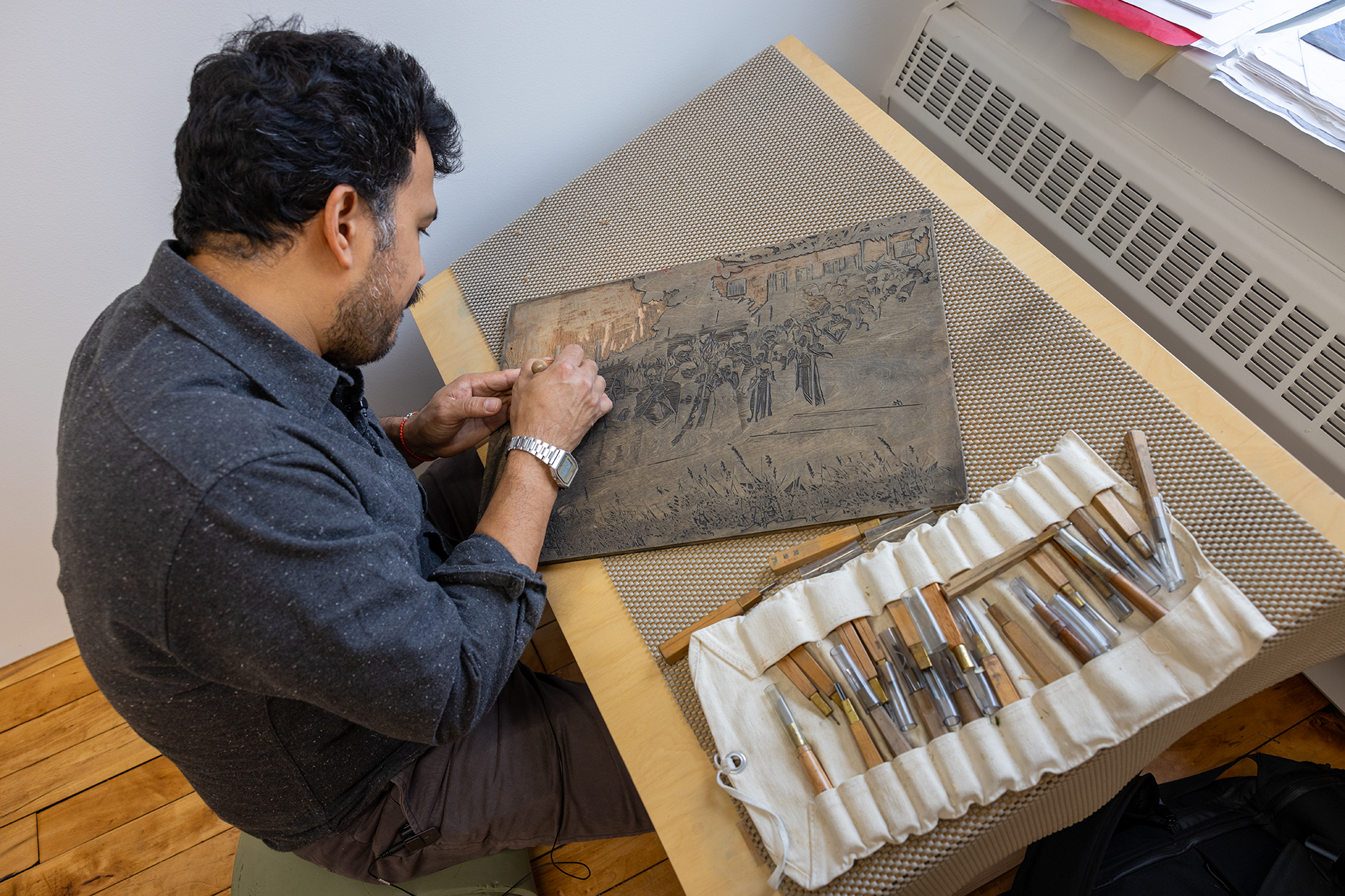 Seated man at work on a wood carving.