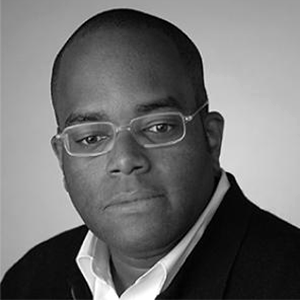 Man wearing glasses, dark jacket and white shirt.