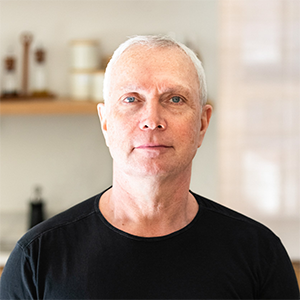 A man in a black shirt looks at the camera.