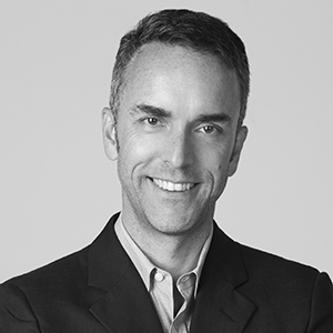 A person smiling wearing a dark suit jacket.