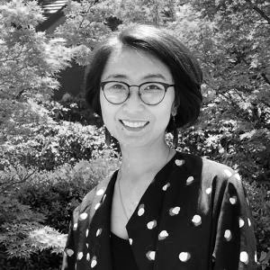 Woman with chin-length dark hair and glasses wearing a polka dot shirt