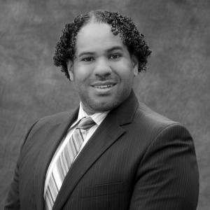 Man with dark curly hair wearing suit and tie 