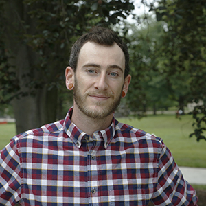 A person with facial hair and wearing a plaid shirt