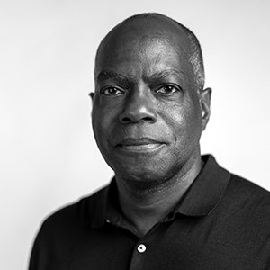 African American man wearing a blue polo in front of a plain white background