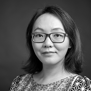 Person with shoulder-length dark hair wearingblack-rimmed glasses