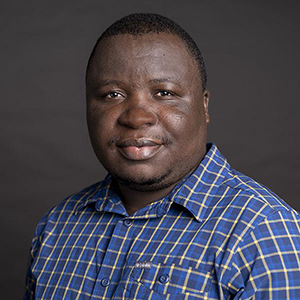 Man dressed in blue checked dress shirt against dark background