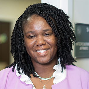 A person in a pink shirt and shoulder length braids