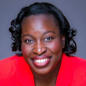 A woman with short black hair in a red shirt smiles at the camera.
