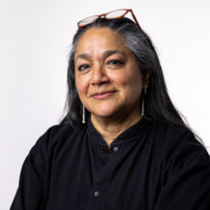 A woman with long dark hair wearing a black shirt looks at the camera.