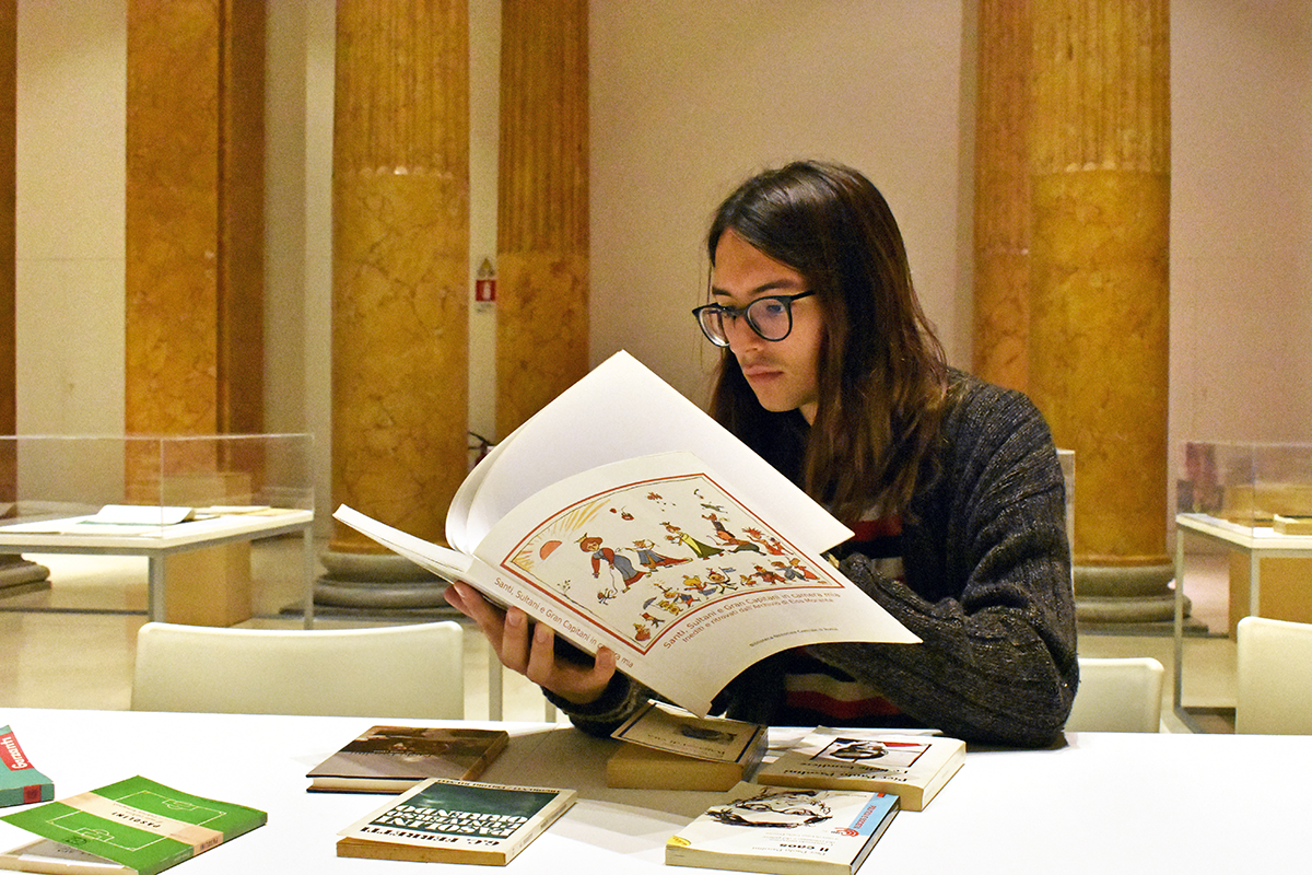 Student seated at a table covered with books reading.