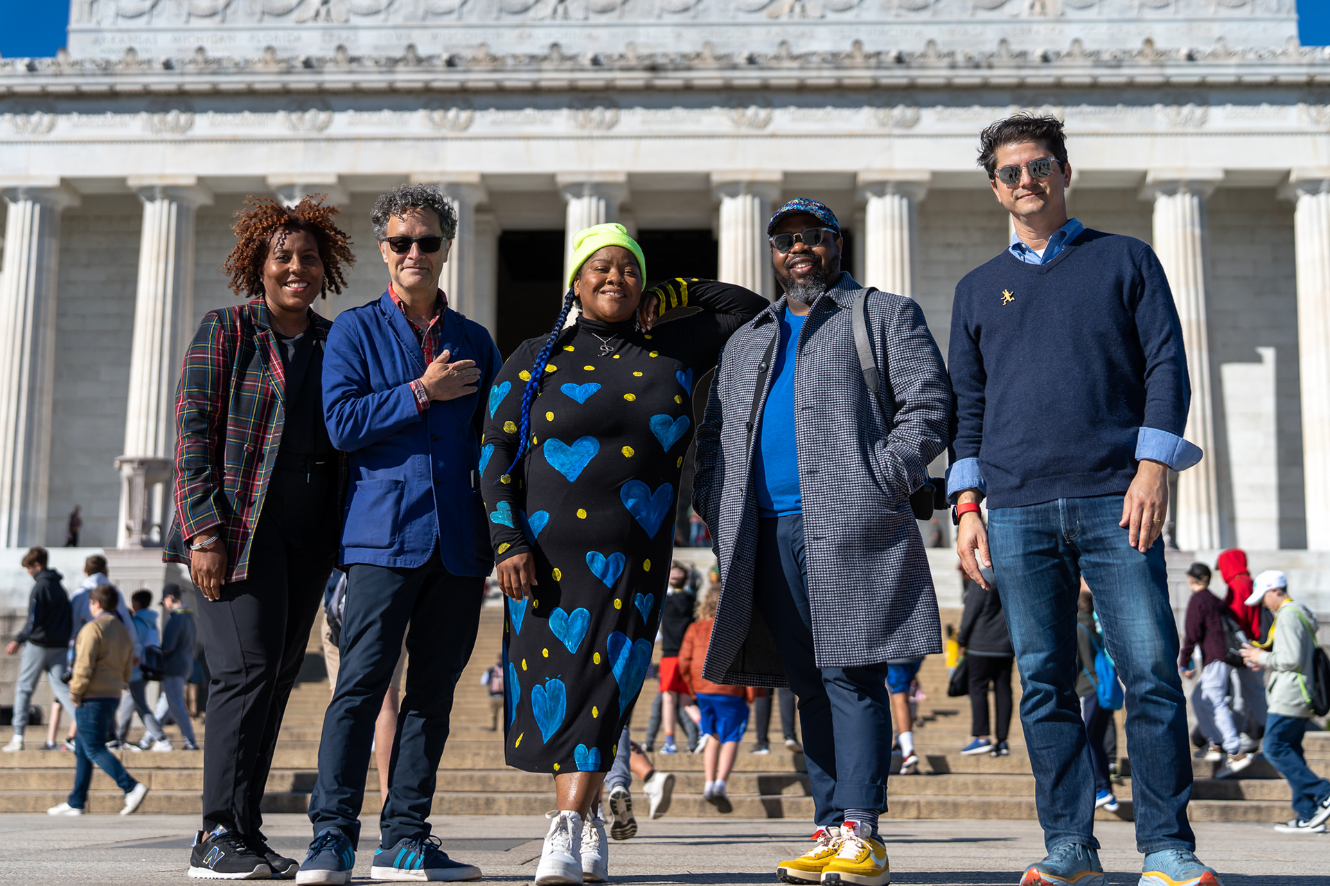 Five adults standing on the steps in front of a large white marble building