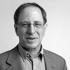 Man wearing glasses and a light shirt and sport coat 