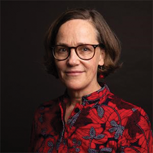 A woman with a red floral shirt and glasses looks at the camera.